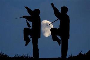 Silhouette of man and woman practicing tai chi by moonlight